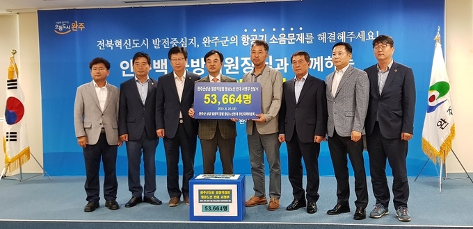 이세우 반대대책위원장이 헬기 소음 피해를 해소해 달라는 완주군민의 서명부를 안규백 위원장에게 전달하고 있다.