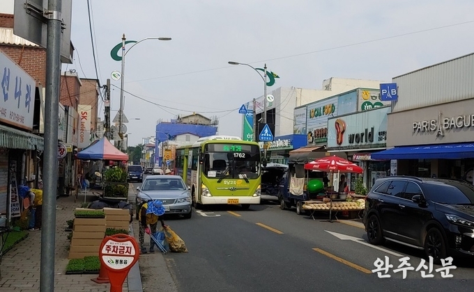 버스가 봉동 재래시장 양측에 주정차된 차량을 피해 가까스로 빠져나오고 있다. 