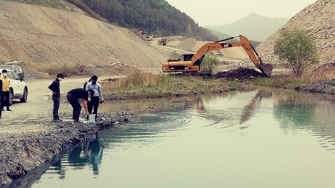 고산면 석산 내 웅덩이 수질 검사를 위해 시료를 채취 중이다.