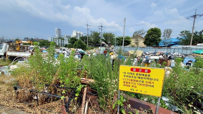 고물상 앞에 설치된 쓰레기 불법투기 경고문. 고물상에 쌓인 낡은 물건들을 경고하는 것 같다.