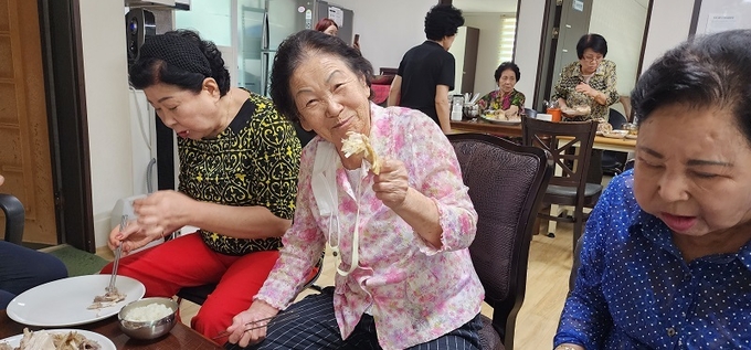 중복엔 토종닭이 최고라며 닭다리를 들고 환하게 웃고 있는 어머니. /이상선 기자