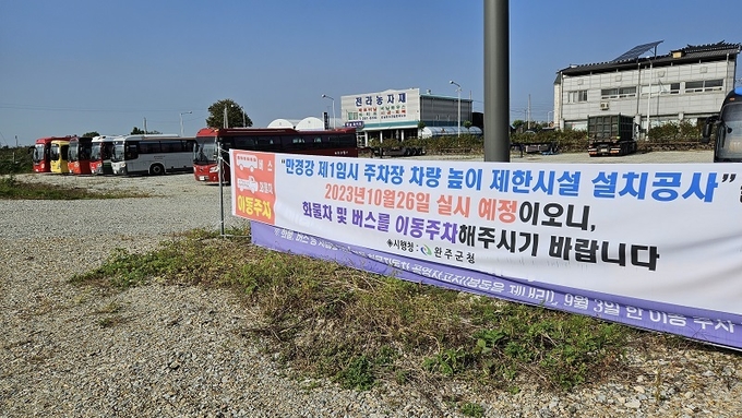 주차장 내 걸린 현수막 뒤로 대형버스가 늘어서 있다.